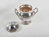 a silver vase with a lid on a white table