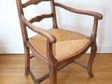 a wooden chair with a woven seat on a hard wood floor