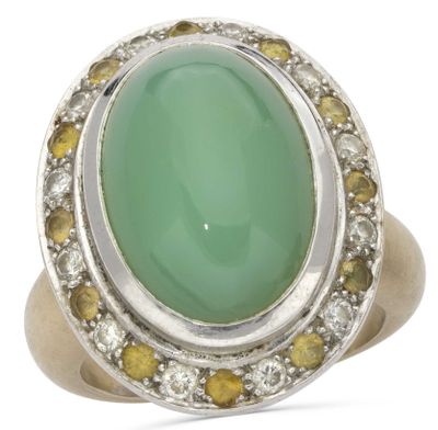 a close up of a ring with a green stone surrounded by yellow and white diamonds