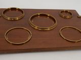 a wooden tray with six brass rings on it
