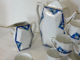 many cups and saucers sitting on a table next to a pitcher