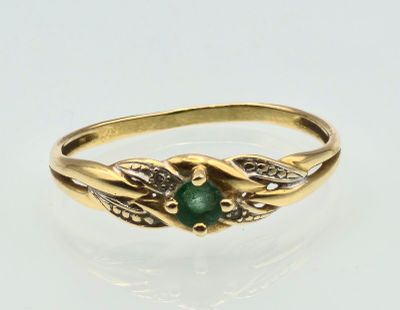 a close up of a gold ring with a green stone