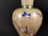 a vase with a bird painted on it sitting on a table