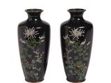 une paire de vases noirs ornés de motifs floraux sur fond blanc