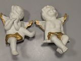 two small figurines of angels sitting on a table