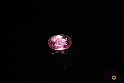 a close up of a pink diamond on a black surface