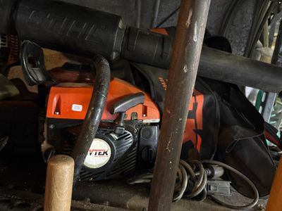 une photo montrant une tronçonneuse et d'autres outils dans un garage