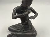 une image représentant une statue en bronze d'un homme assis à genoux
