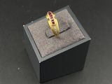 a close up of a gold ring with a red stone in it
