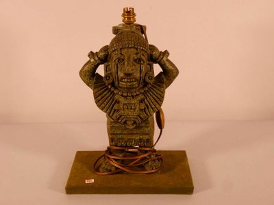 une statue représentant un homme tenant une lampe posée sur une table