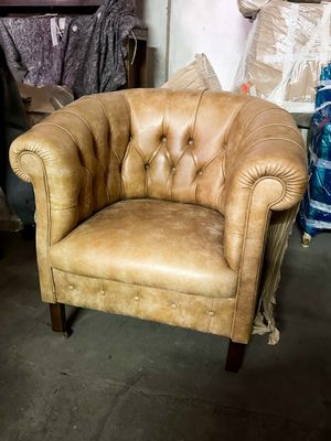 a tan leather chair sitting in a room with other furniture