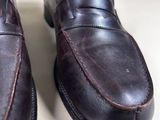pair of brown leather shoes on a white surface with a brown leather strap
