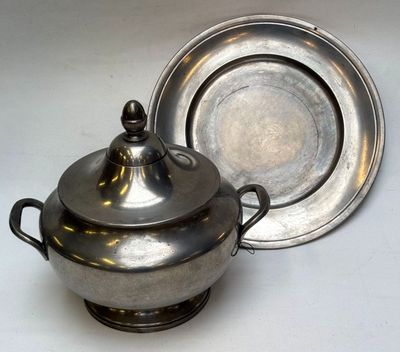 un plat en argent avec un couvercle en argent, à côté d'un bol en argent