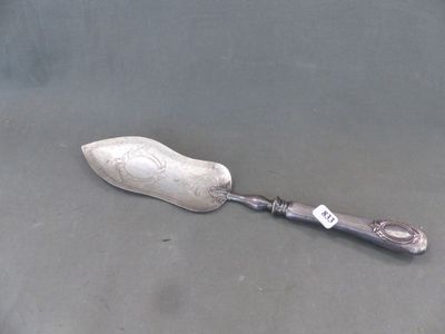 une cuillère en argent avec un manche en argent posée sur une surface grise