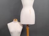 two white mannequins on a wooden tripod stand against a gray background