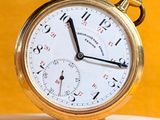 a gold pocket watch sitting on top of a piece of wood