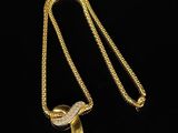 a gold plated necklace with a leaf pendant on a black background