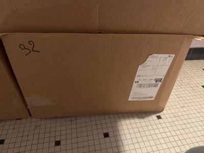 une boîte en carton posée sur un sol carrelé