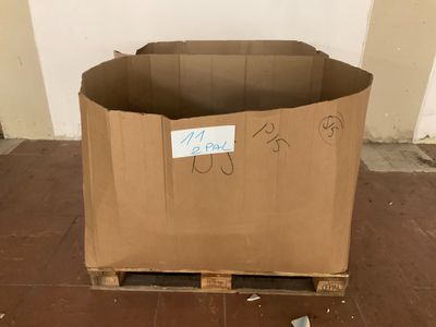 un carton posé sur une palette, sur lequel figurent des inscriptions