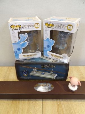 deux figurines Harry Potter posées sur une étagère en bois, à côté d'une boîte contenant des figurines Harry Potter