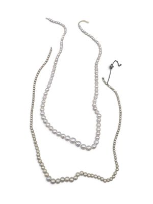 two strands of white pearls and a silver chain on a white background