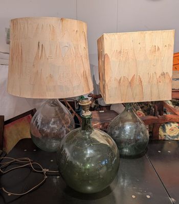 trois lampes en verre vert posées sur une table, avec une horloge en arrière-plan