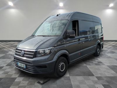 La camionnette grise est garée dans une grande pièce au sol carrelé en damier.