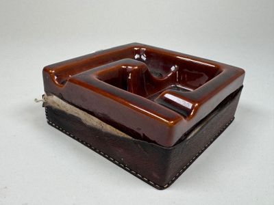 un cendrier marron et noir posé sur une table blanche