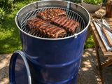 a barbecue grill with ribs cooking on it in the backyard