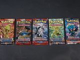 Quatre paquets de cartes à collectionner Pokémon sont alignés sur une table