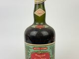 an old bottle of liquor sitting on top of a white surface