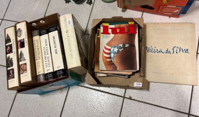 many books in a box on the floor next to a camera
