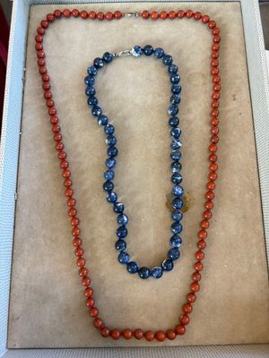 deux colliers dans une boîte, dont un collier composé de perles rouges et bleues
