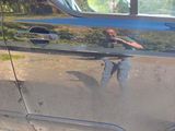 a man taking a picture of himself in the reflection of a car door
