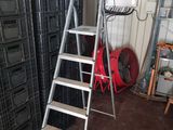 une échelle appuyée contre un mur, à côté d'une pile de caisses