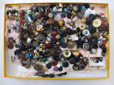 une boîte remplie de boutons assortis posée sur une table