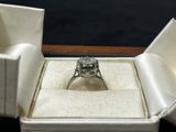 une bague en diamant dans une boîte blanche sur fond noir