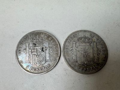 two silver coins sitting side by side on a white surface