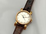 gros plan d'une montre sur une surface blanche avec un bracelet marron
