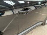 a close up of a car door handle with a reflection of a person in the background