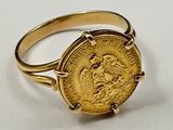 une image représentant une bague en or sur laquelle repose une pièce d'or