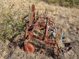 a rusted plow sitting in the middle of a field