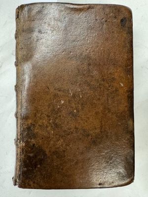 un vieux livre en cuir marron posé sur une table blanche