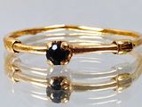 une photo en gros plan d'une bague en or sertie d'une pierre noire
