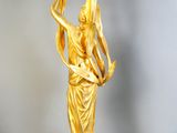 a gold statue of a woman holding a bird in her hand