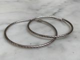 a pair of silver bracelets sitting on top of a marble counter