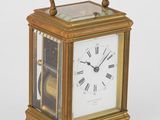 une petite horloge en or avec des chiffres romains