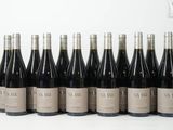 six bouteilles de vin sont alignées sur une surface blanche