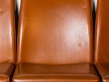 three brown leather chairs are lined up against a white wall