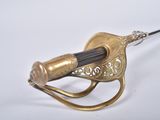 a small brass object with a black handle on a white surface